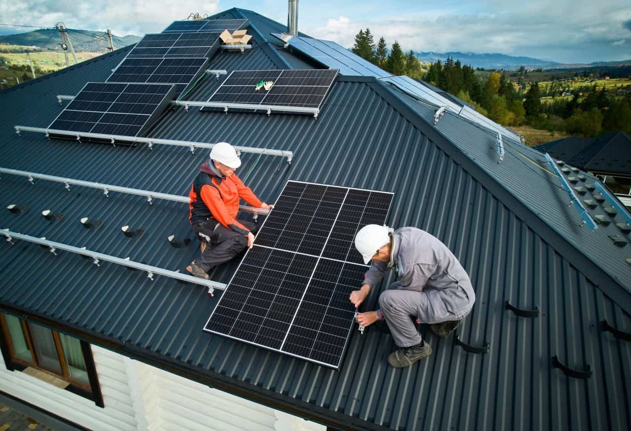 technicians installing photovoltaic solar panels on roof of house e1696237312747.jpg